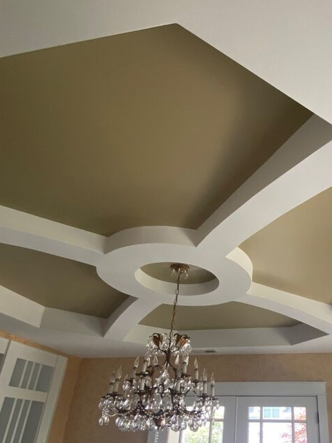 Ceiling with geometric coffers, chandelier, and windowed wall below