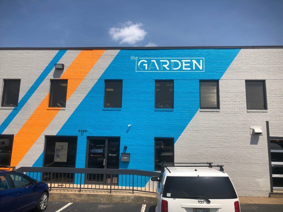 Blue-and-orange storefront labeled “GARDEN” with parked cars in front