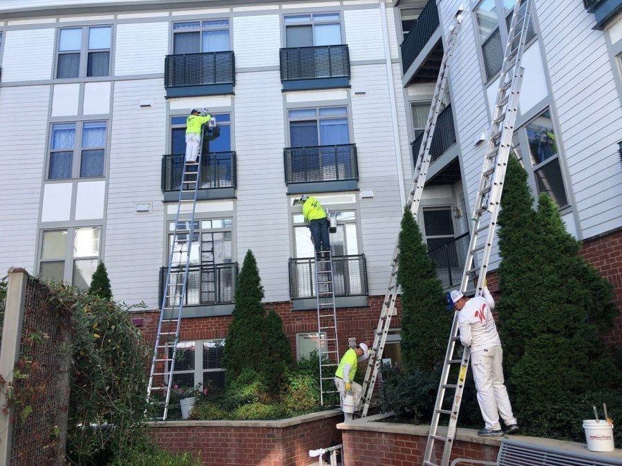 Workers on ladders cleaning or repairing a building facade and windows