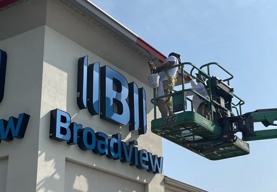 Worker in a lift installing signage on the BBI Broadview building exterior
