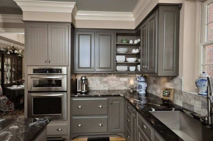 Modern kitchen with gray cabinets, stainless appliances, black countertops, and a tiled backsplash
