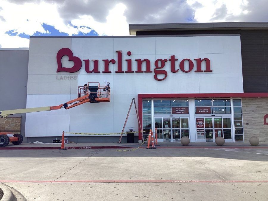 Burlington storefront with a lift worker painting the sign above the entrance