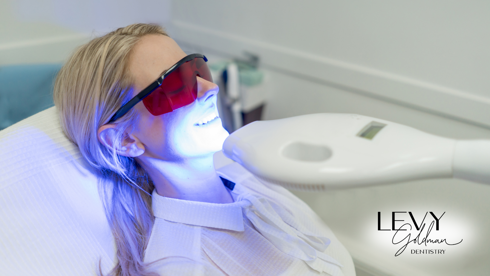 A woman is getting her teeth whitened in a dental office.