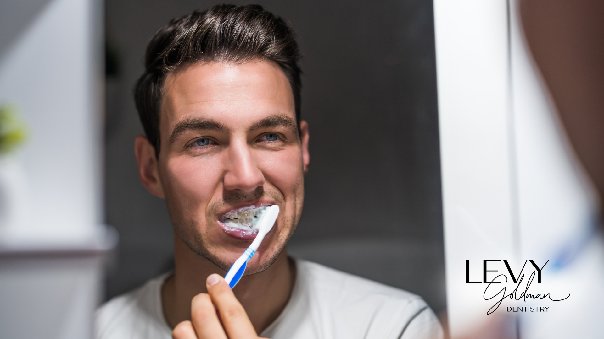 A man is brushing his teeth in front of a mirror.