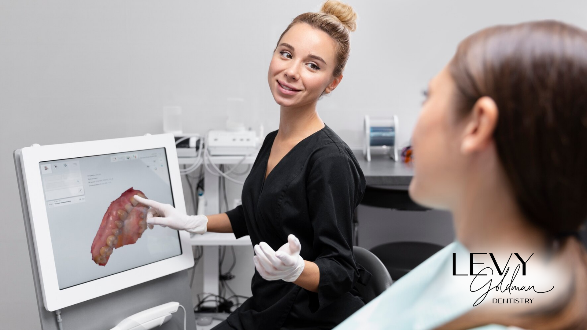 A woman is sitting in a dental chair looking at a computer screen.