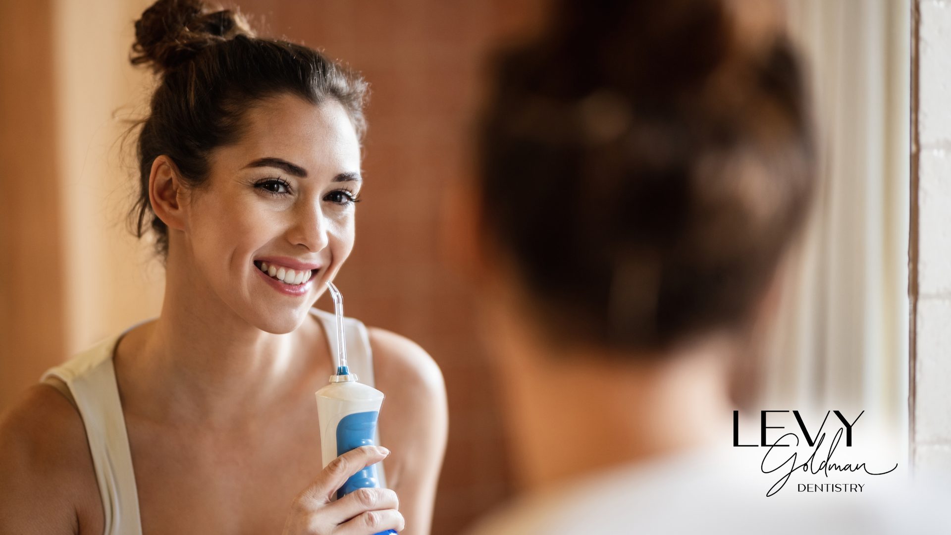 A woman is using an electric toothbrush to clean her teeth in front of a mirror.