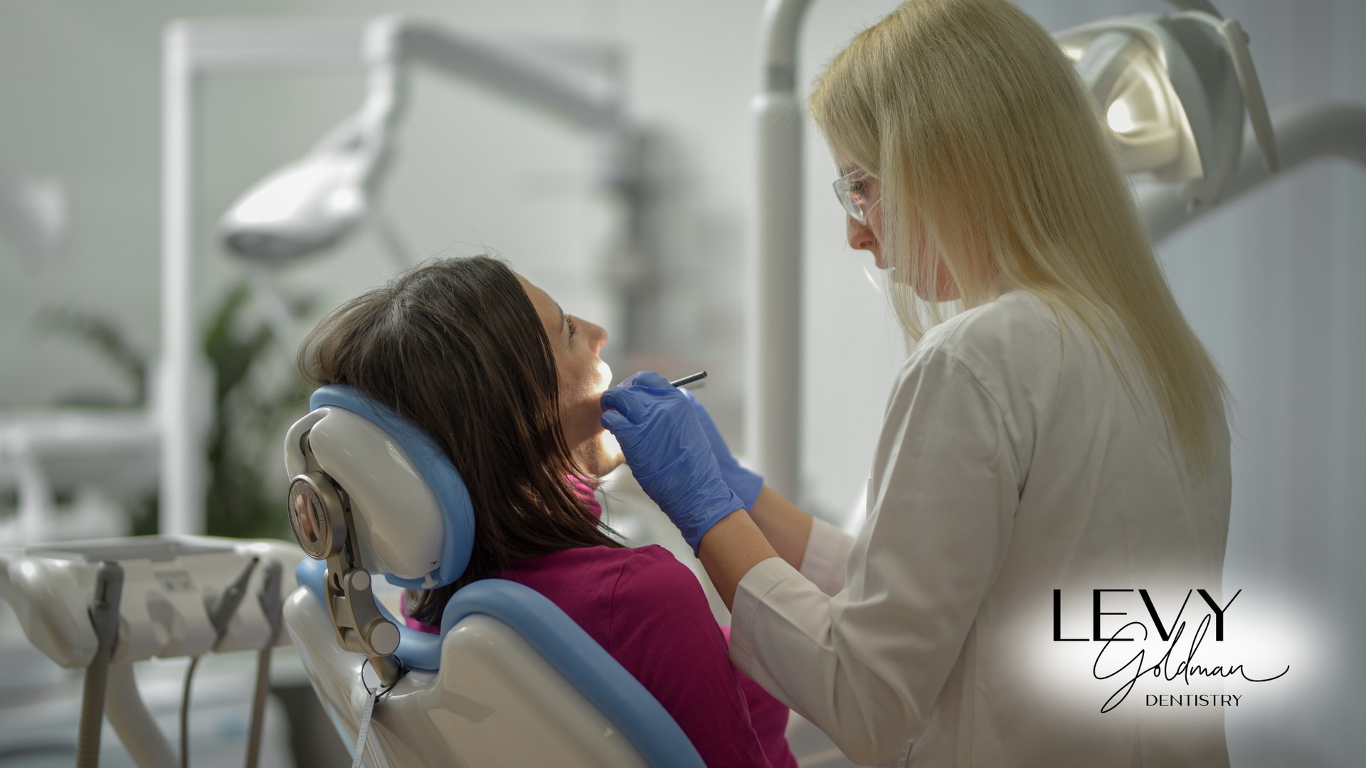 A woman is sitting in a dental chair getting her teeth examined by a dentist.