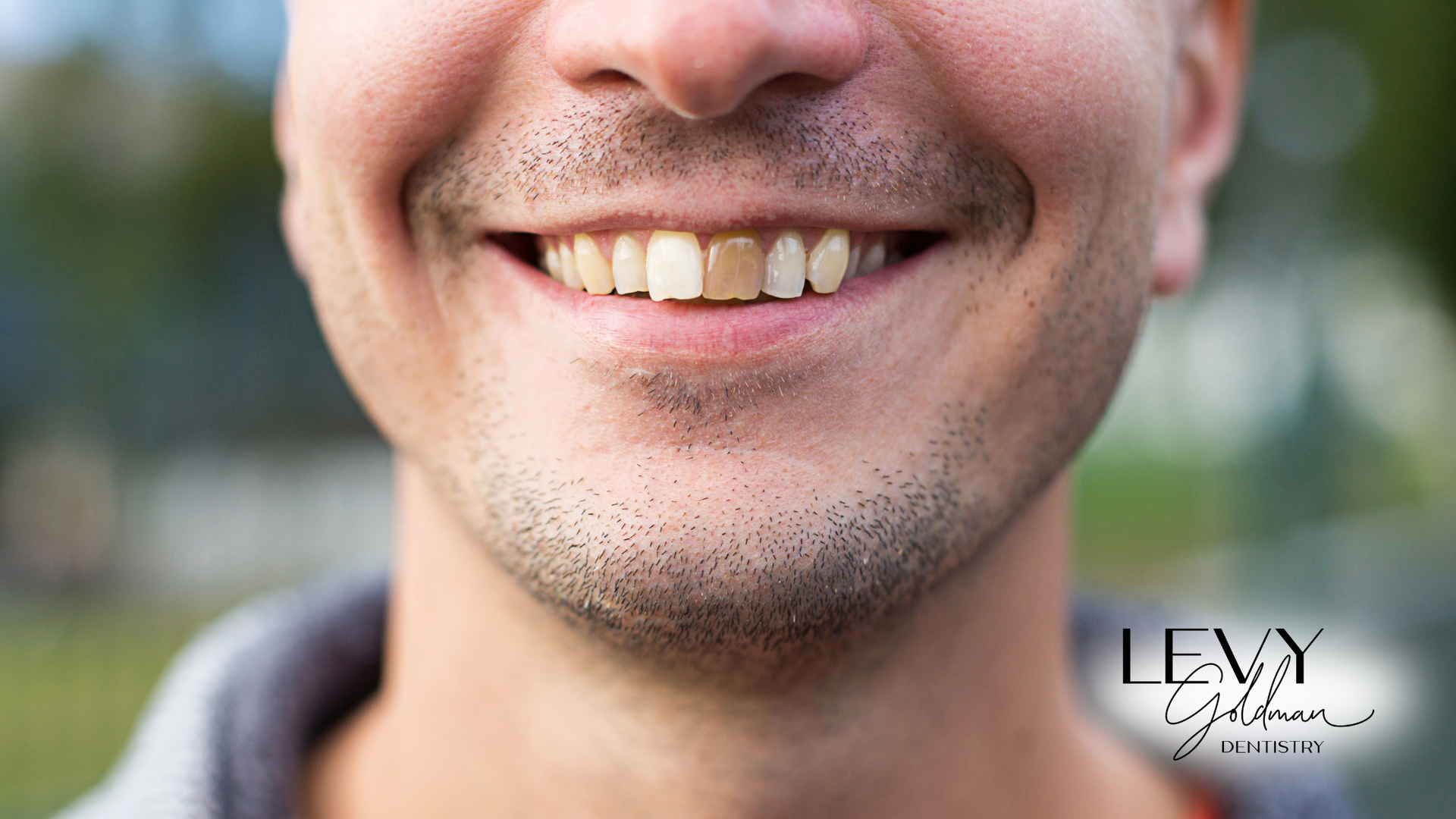 A close up of a man 's mouth with a beard smiling.