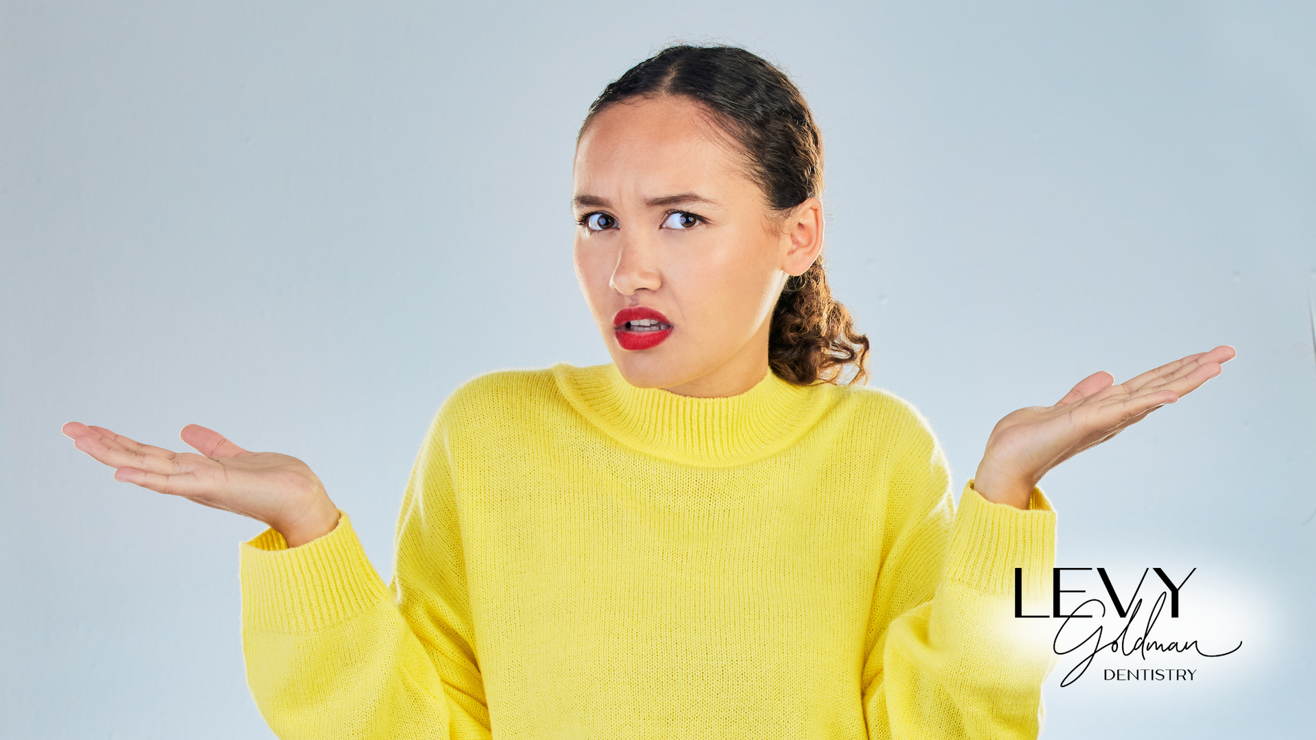 A woman in a yellow sweater is shrugging her shoulders.