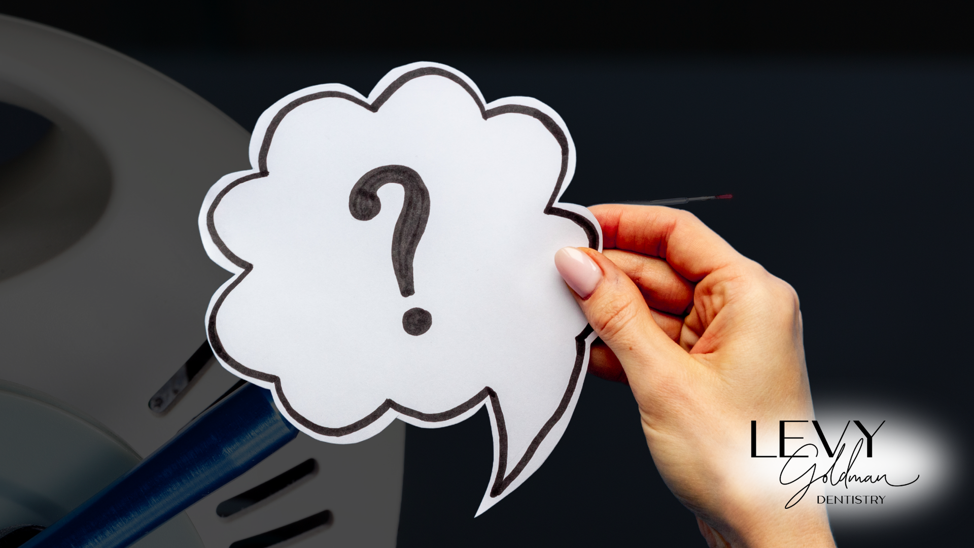 A person is holding a speech bubble with a question mark in it