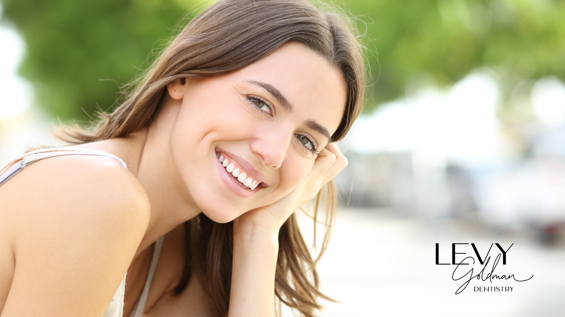 A close up of a woman smiling with her hand on her chin.