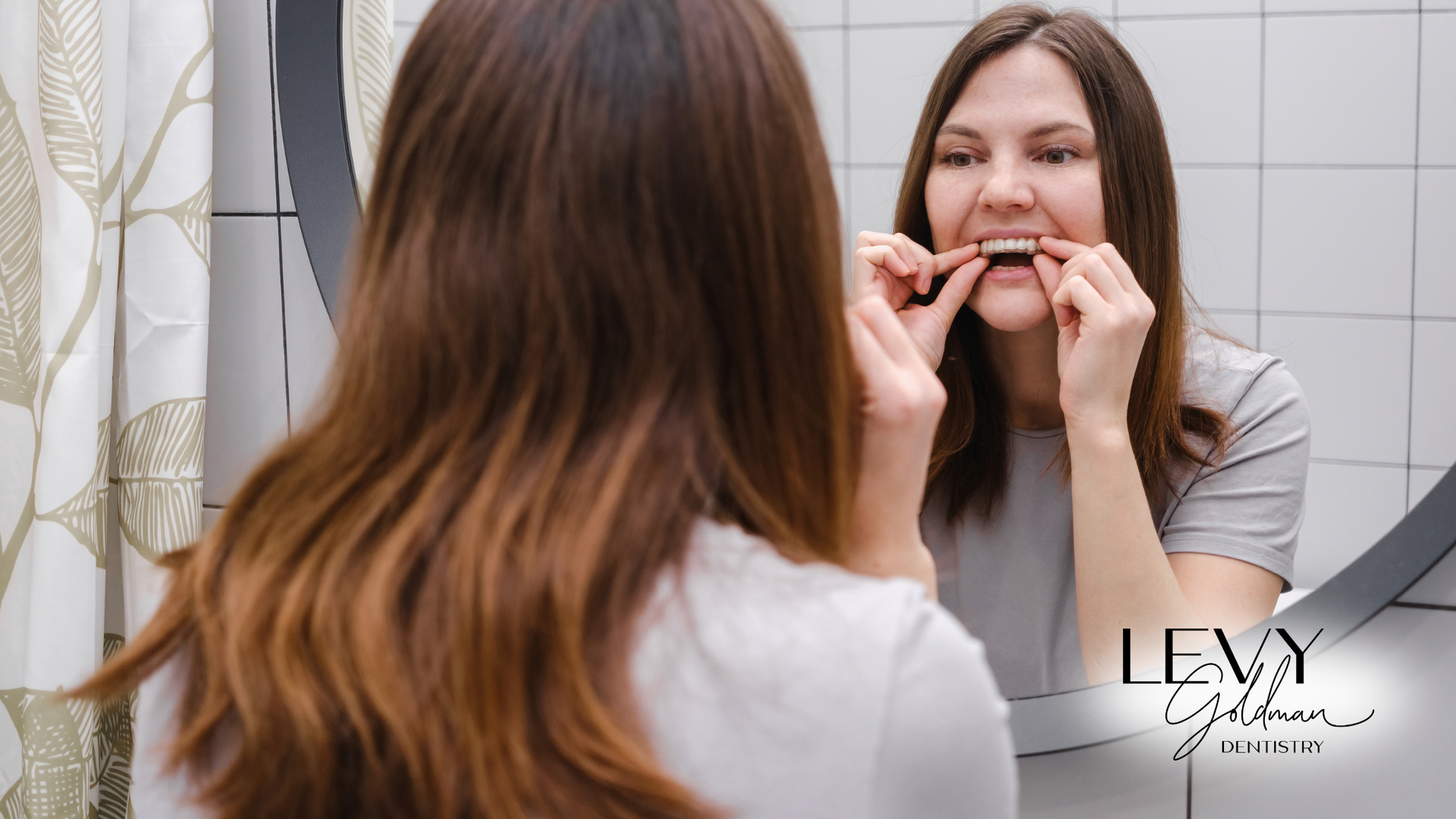 A woman is putting on Invisalign clear aligners.
