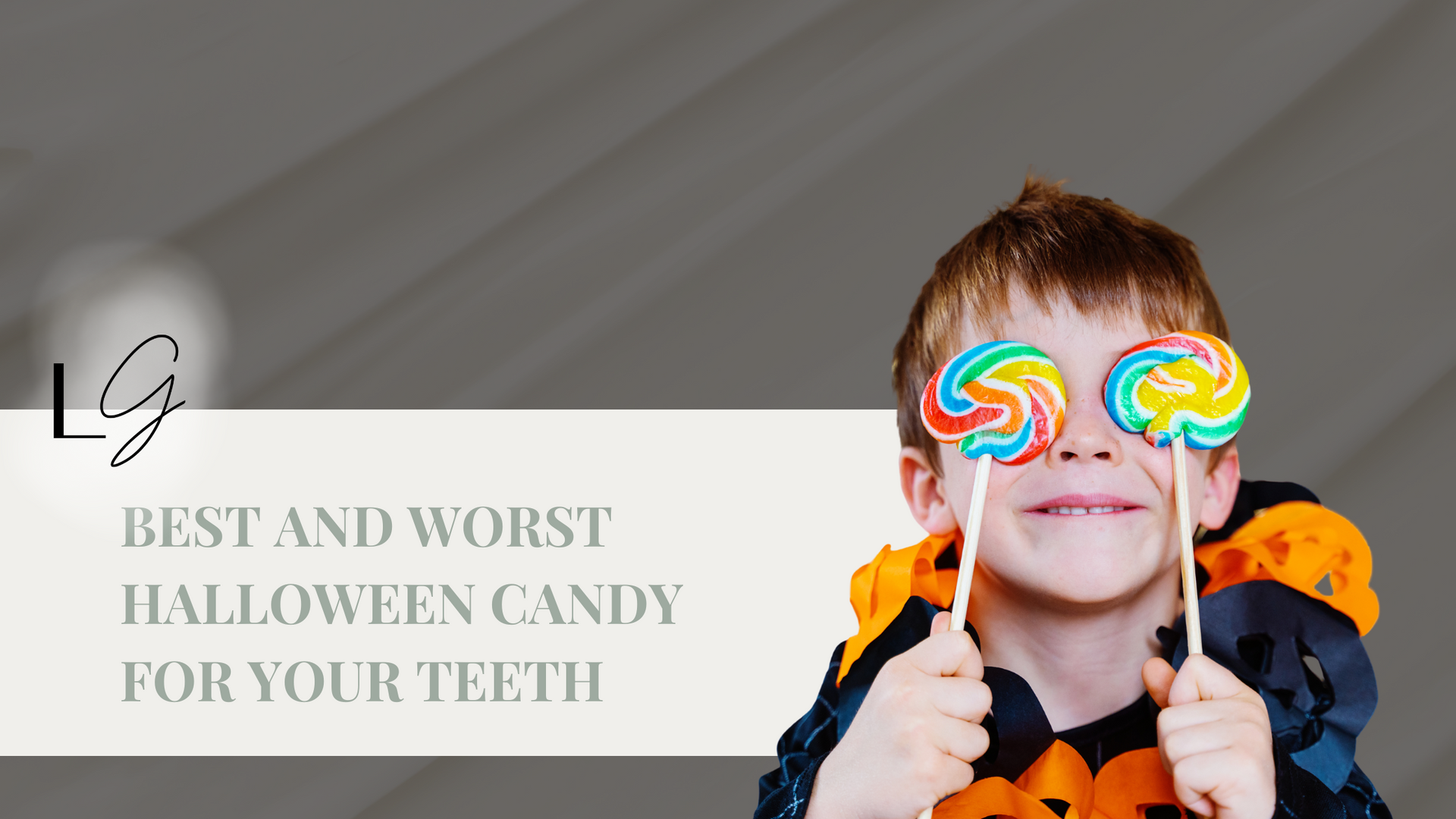 A boy in a halloween costume is holding two lollipops in front of his eyes.