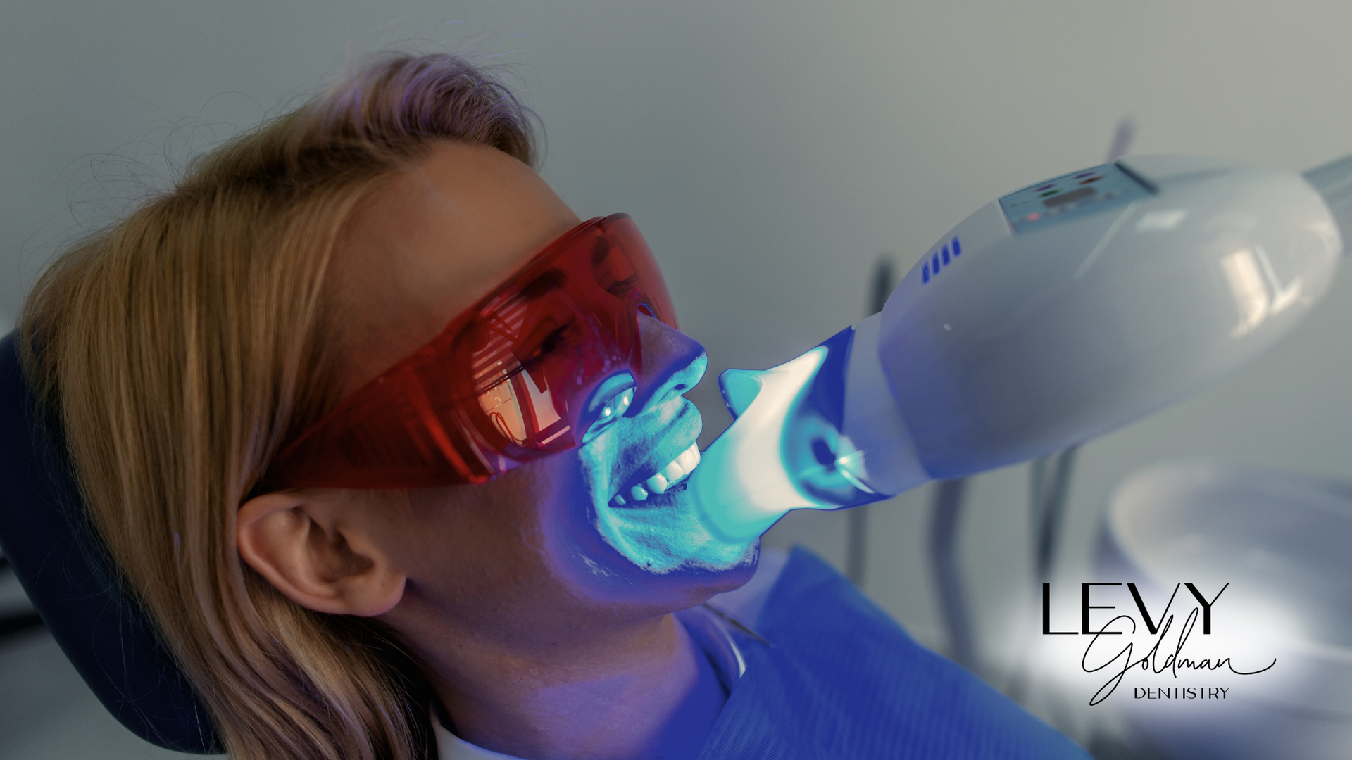 A woman is getting her teeth whitened in a dental office.
