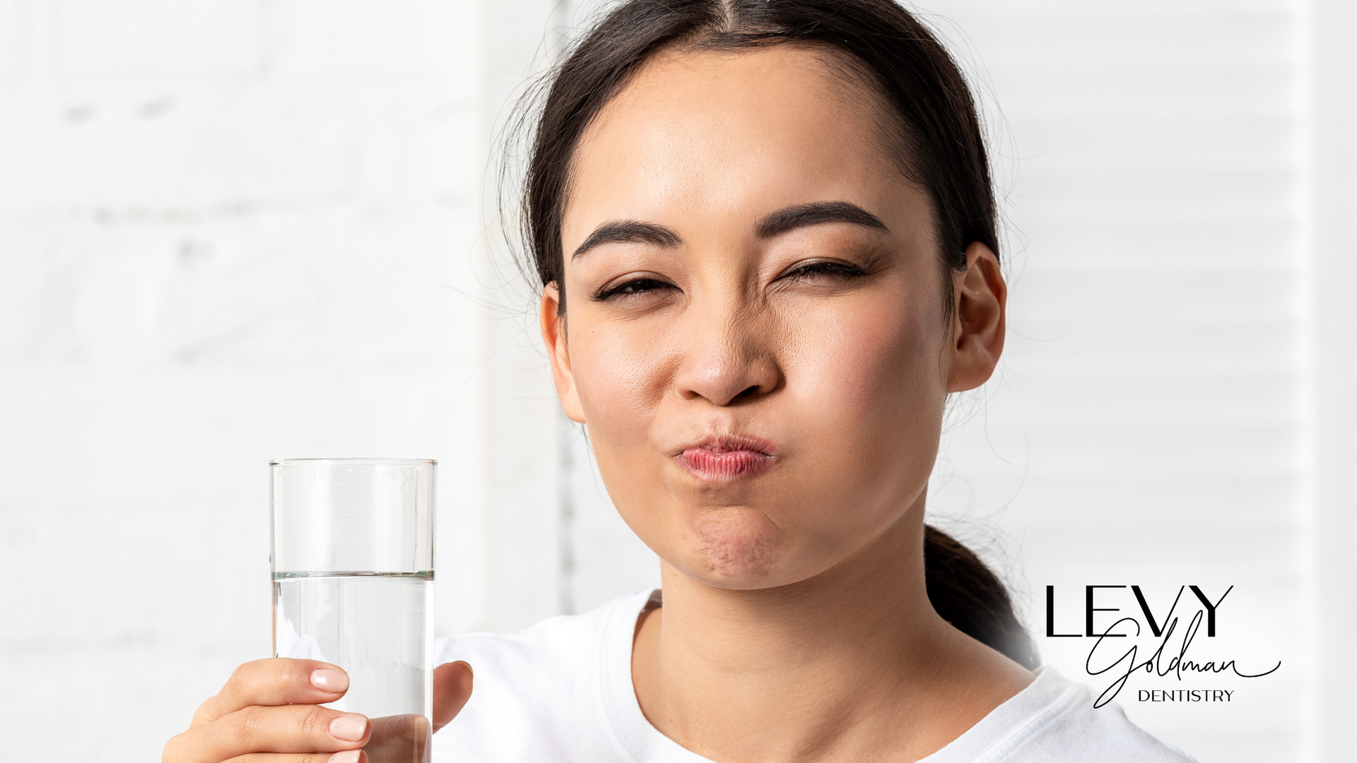 A woman is holding a glass of water in her hand.