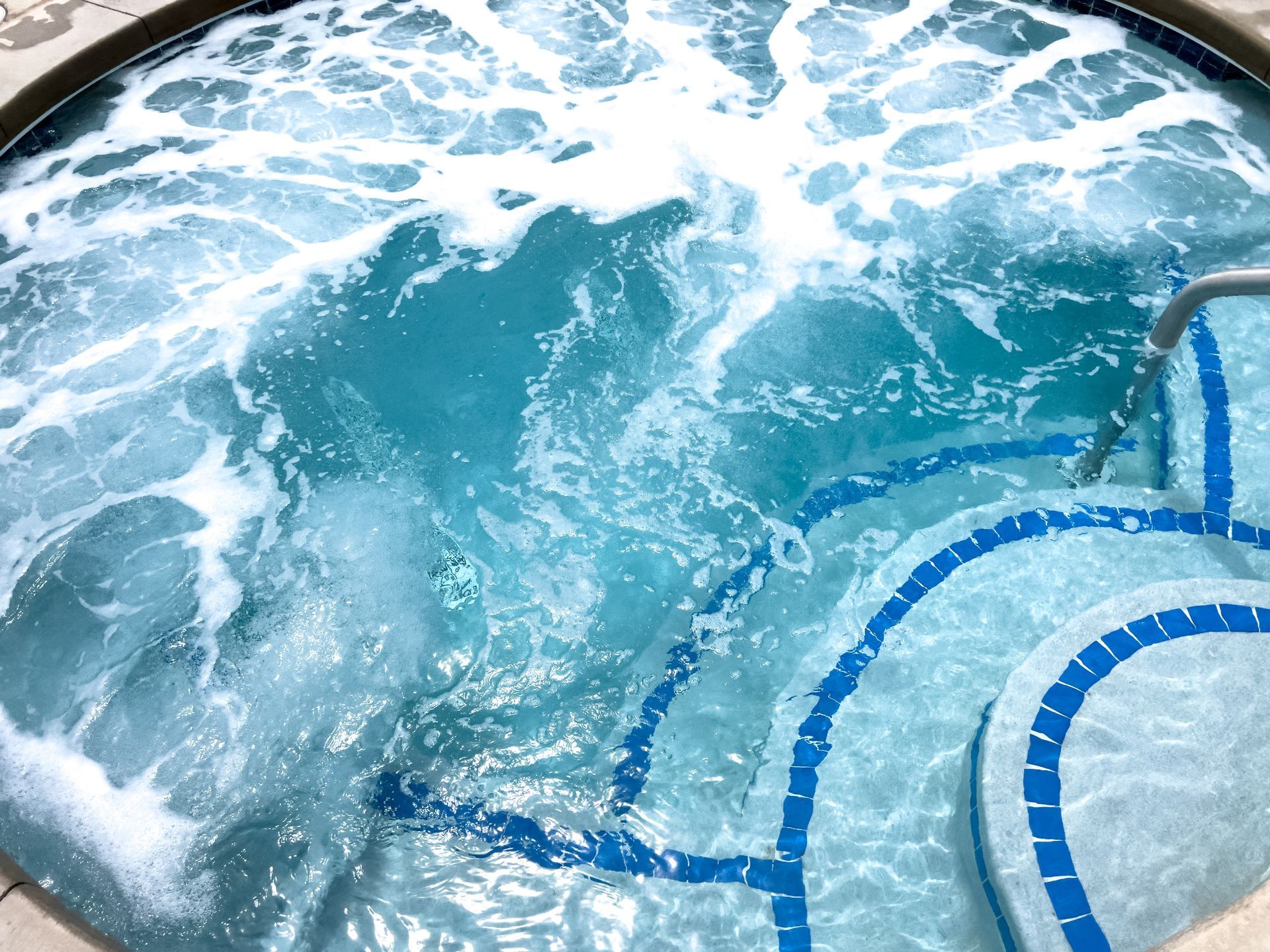 Blue-tiled swimming pool with churning water and visible pool steps
