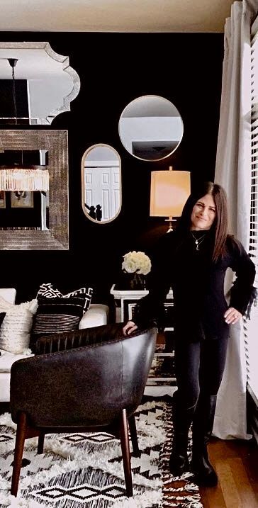 A woman is standing in a living room next to a chair.