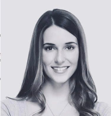 A woman with long hair is smiling in a black and white photo.