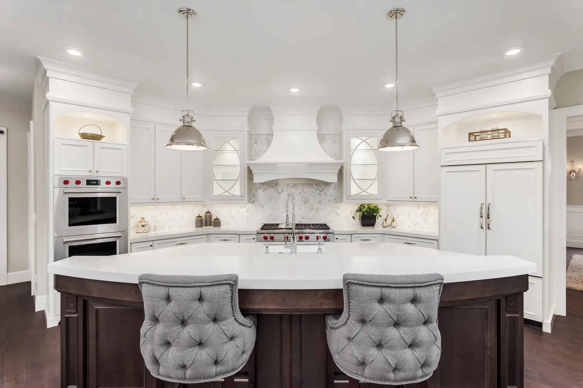 A kitchen in a new home with a large island and two chairs.