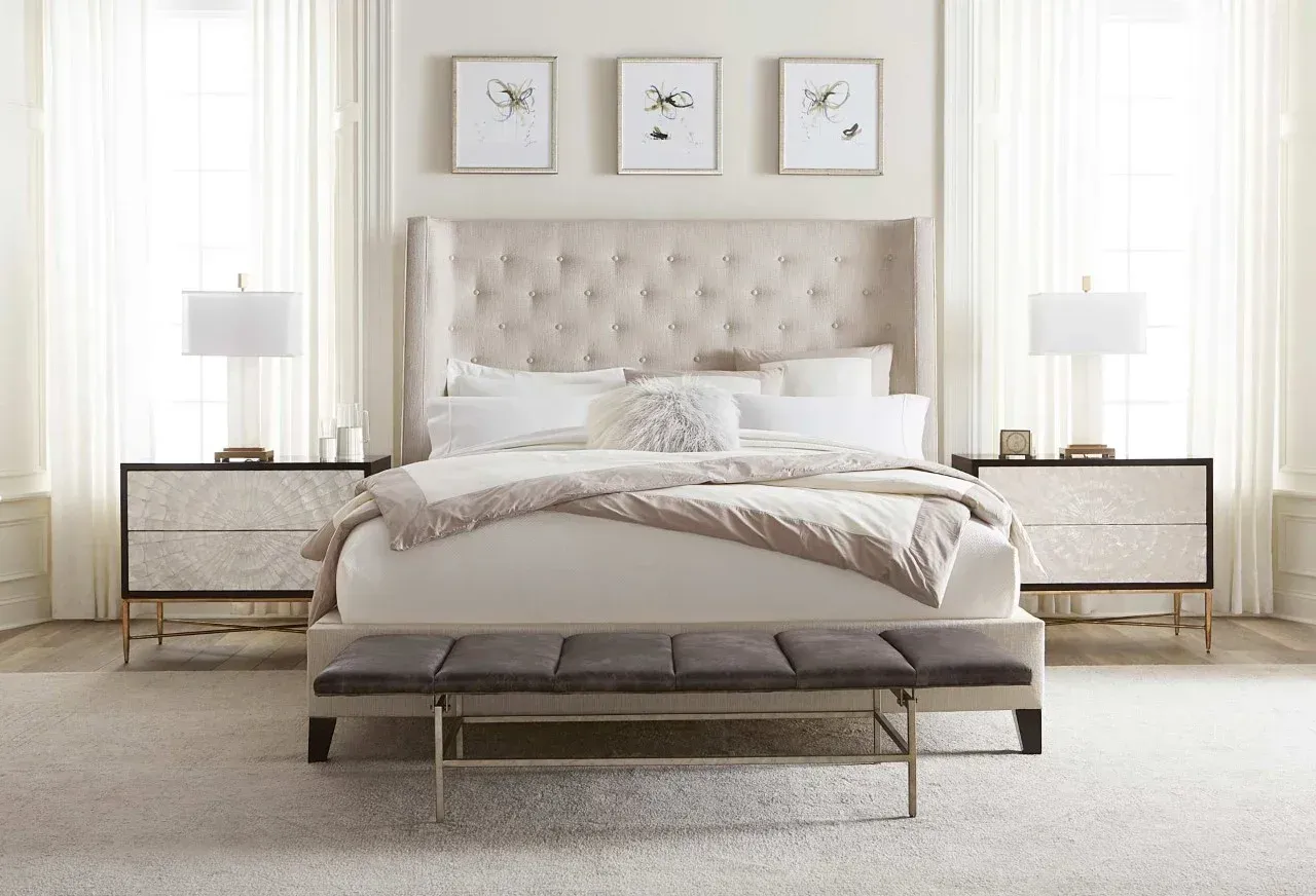 A bedroom with a bed , two nightstands , and a bench.