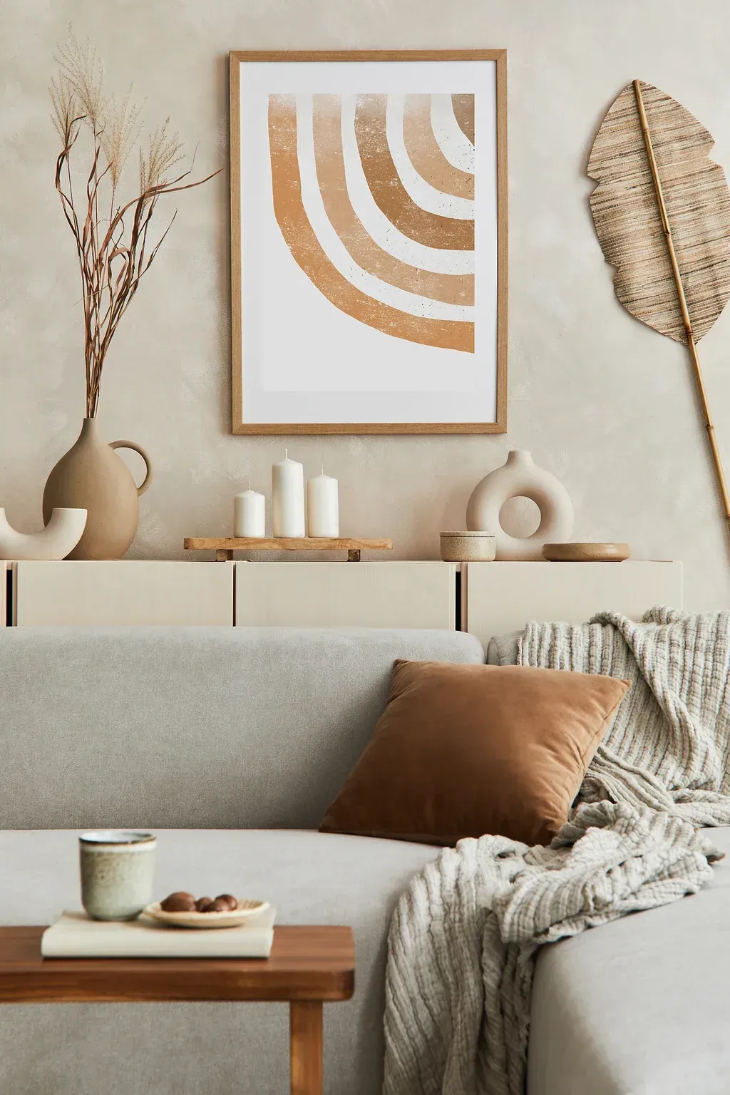 A living room with a couch , table , vases and a picture on the wall.
