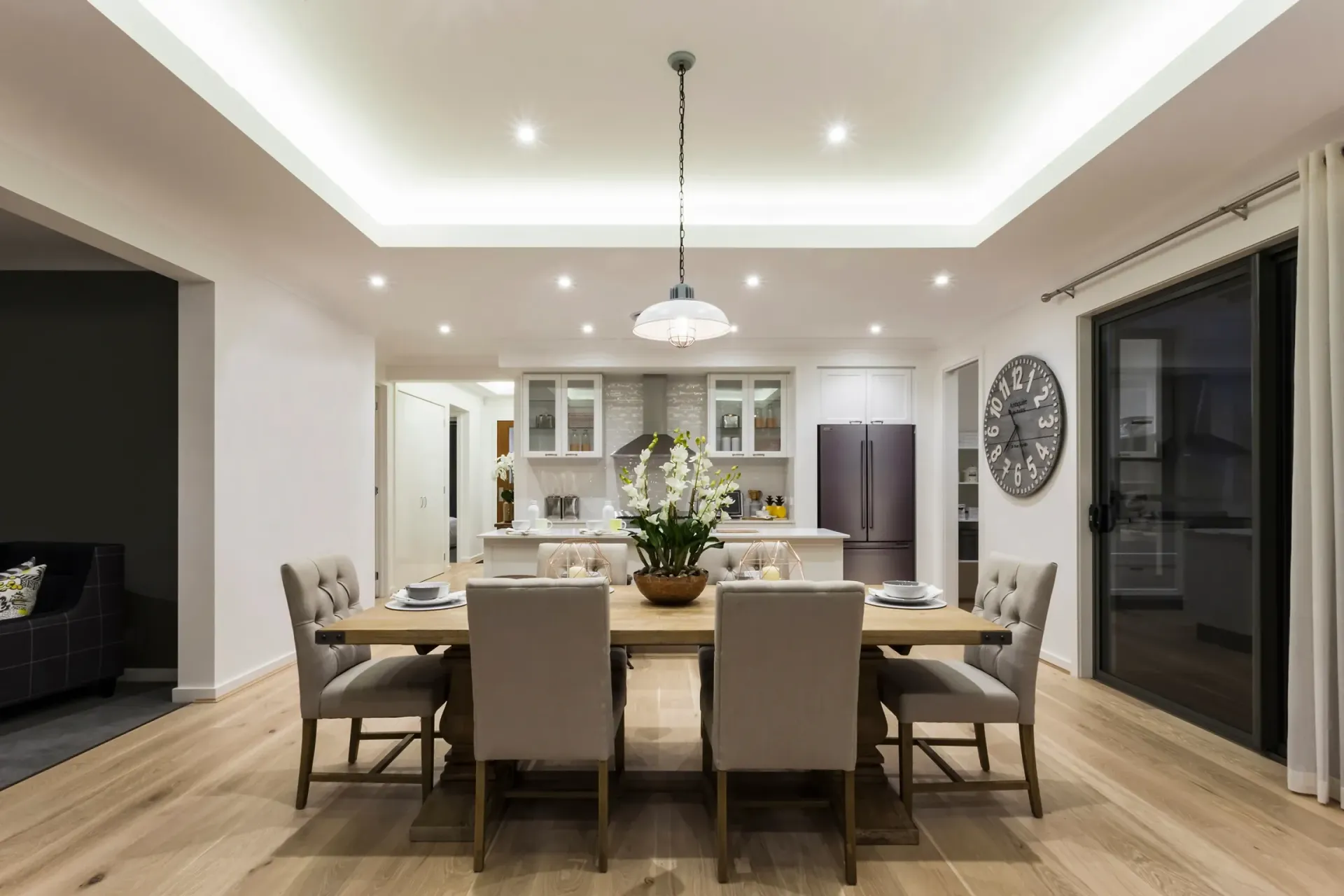 A dining room with a table and chairs and a clock on the wall.