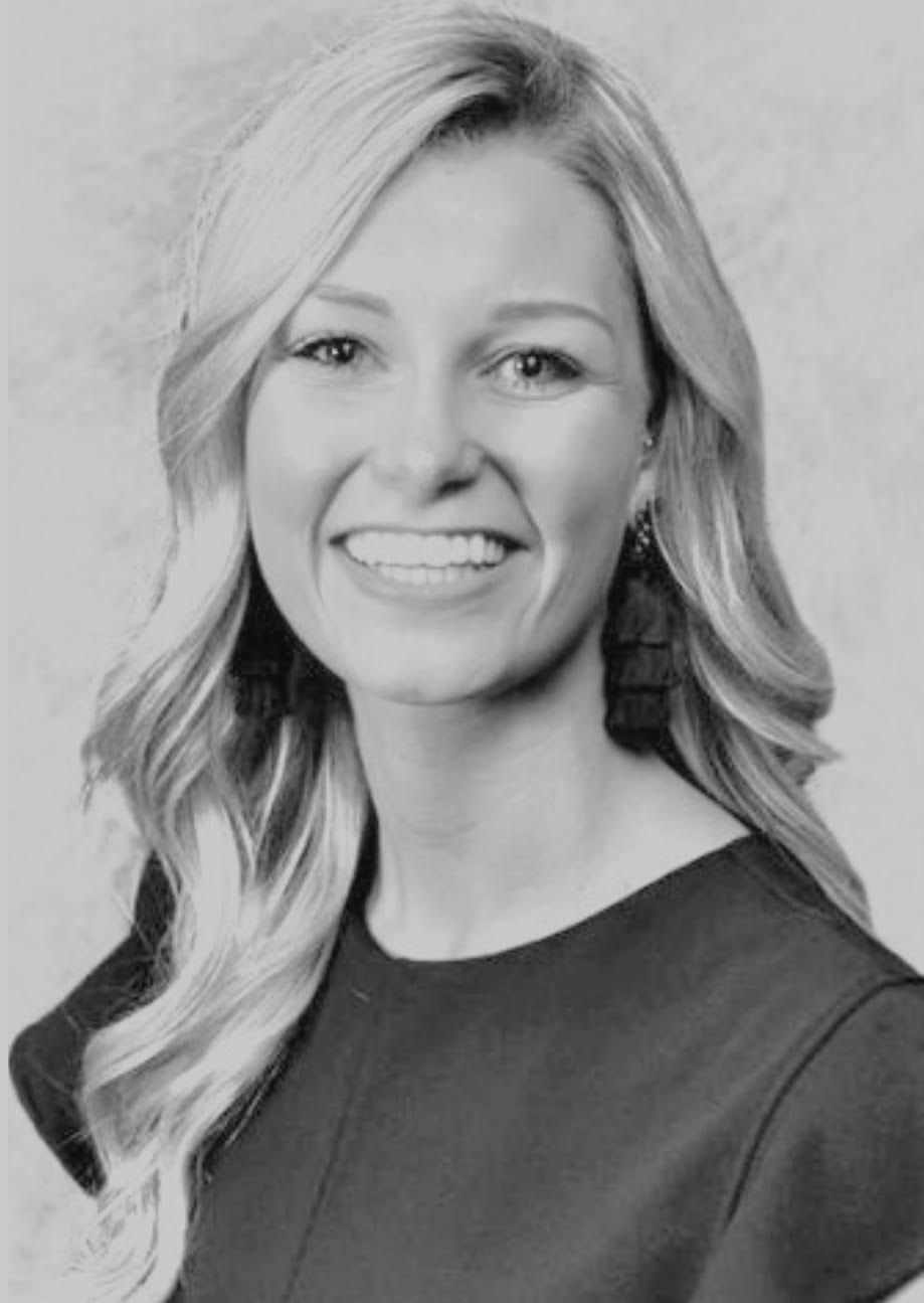 A woman with long blonde hair is smiling in a black and white photo.