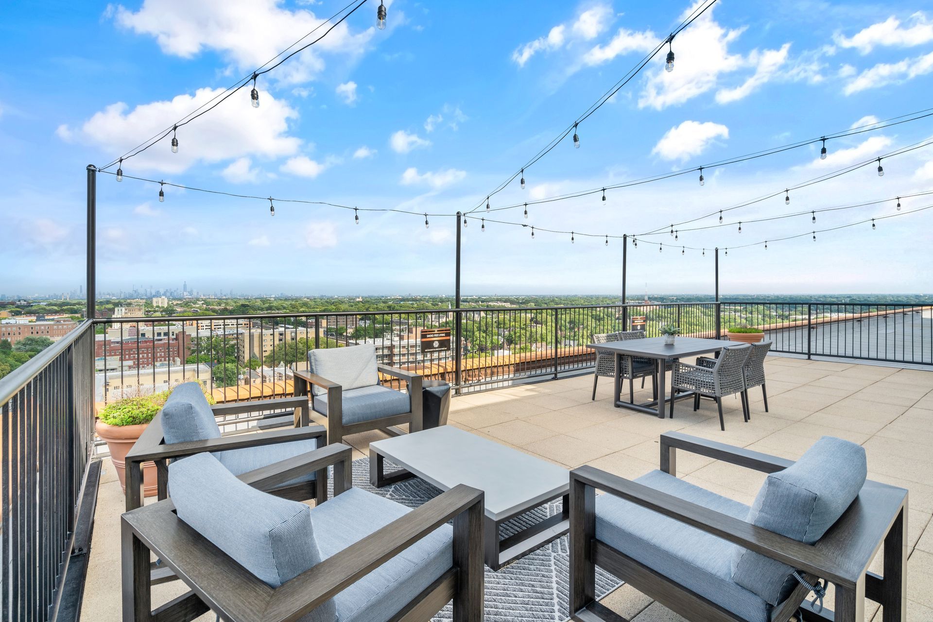 outdoor seating and dining area under string lights on the rooftop of 100 Forest Place apartment building in Oak Park, IL