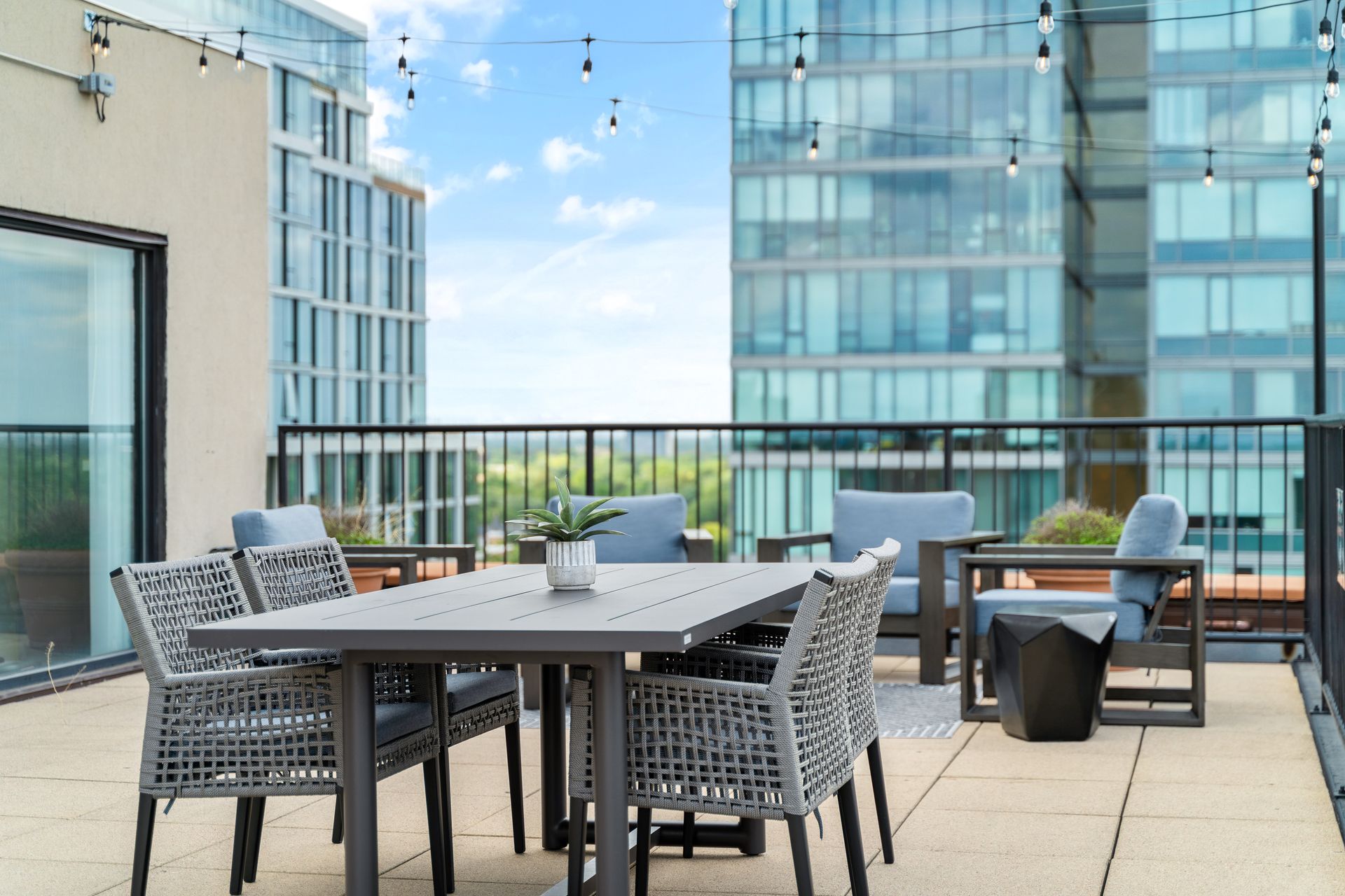 outdoor dining table and lounge area under string lights on 100 Forest Place Apartment's rooftop with views of Oak Park, IL