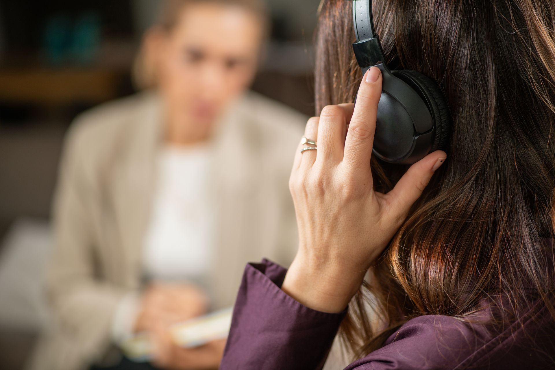 Woman wearing headphones in a counseling session with a blurred person in the background