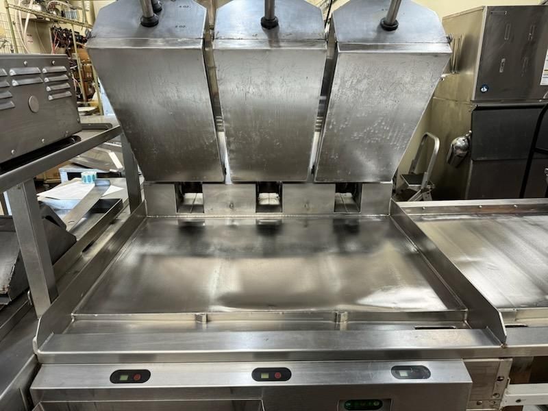 A stainless steel machine is sitting on top of a counter in a kitchen.
