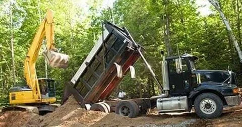 A man is pumping a hose into a septic tank.