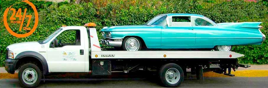 Un coche azul está siendo remolcado por una grúa