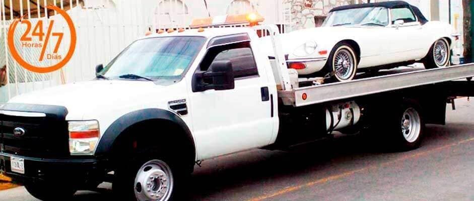 Una grúa blanca con un coche blanco en la parte trasera.