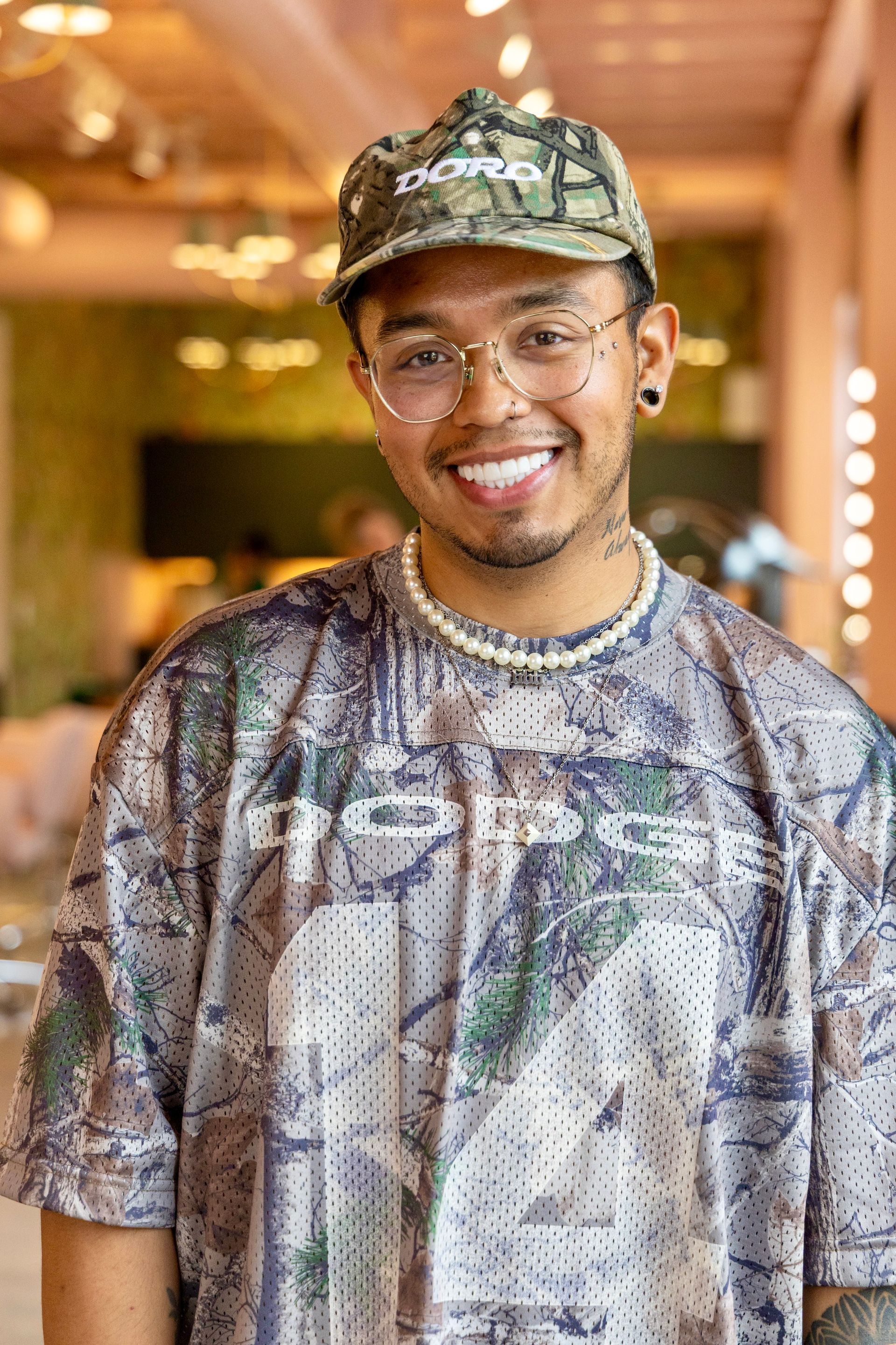 A man with a tattoo on his arm is standing with his arms crossed and smiling.