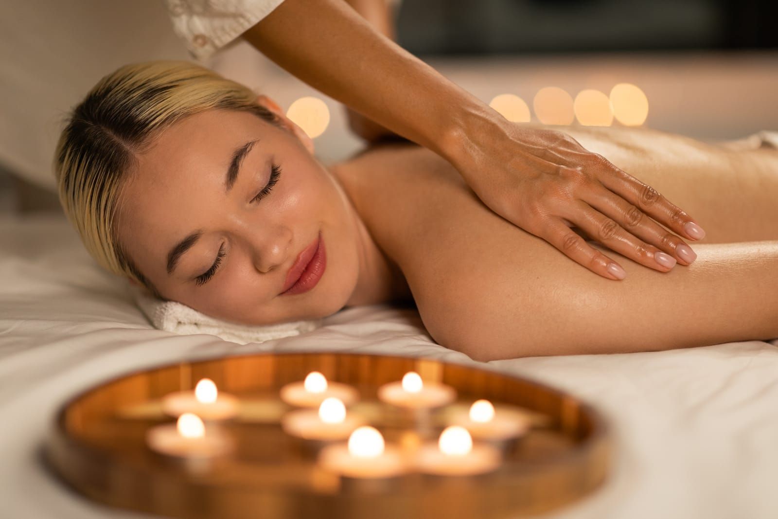 Person receiving a relaxing swedish massage with candles glowing in a spa setting