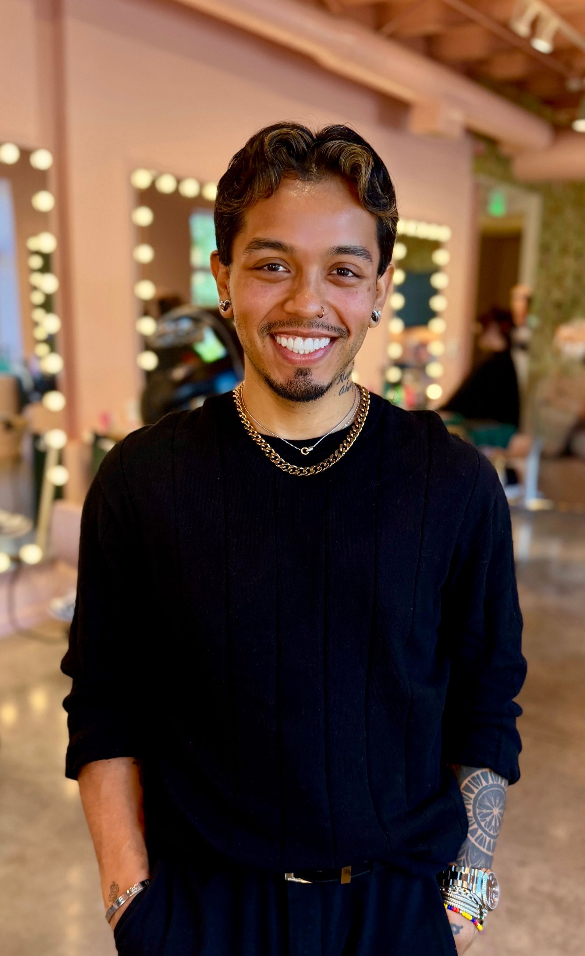A man with a tattoo on his arm is standing with his arms crossed and smiling.