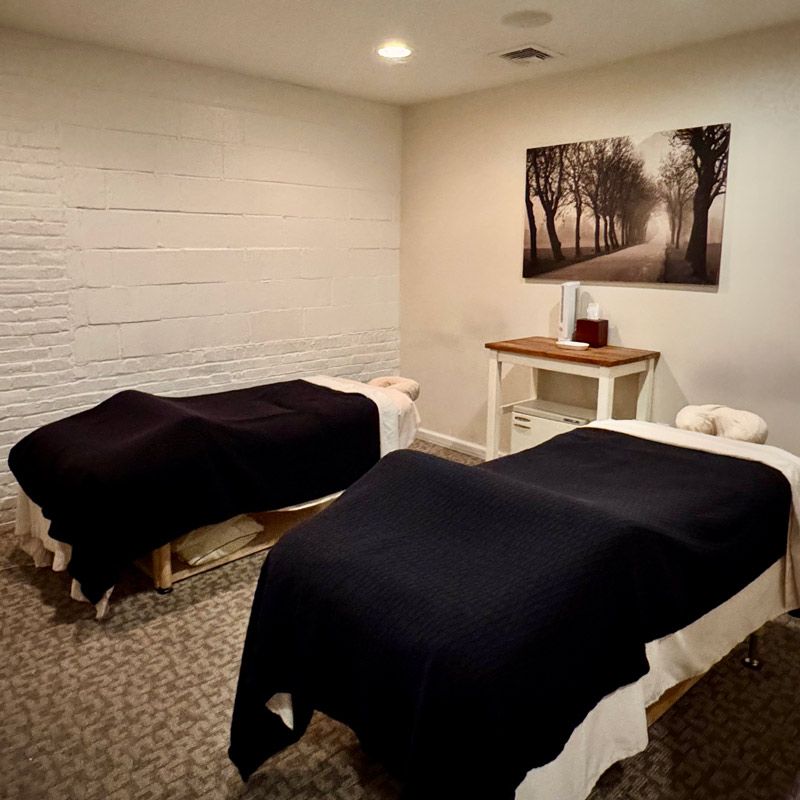 Two massage beds in a room with a painting on the wall above them