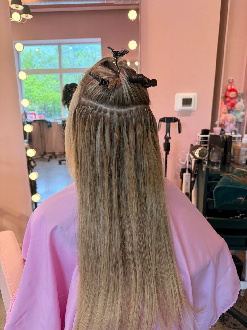 Back view of long highlighted hair being styled at Luxe Salon in Lancaster PA with hair extensions.