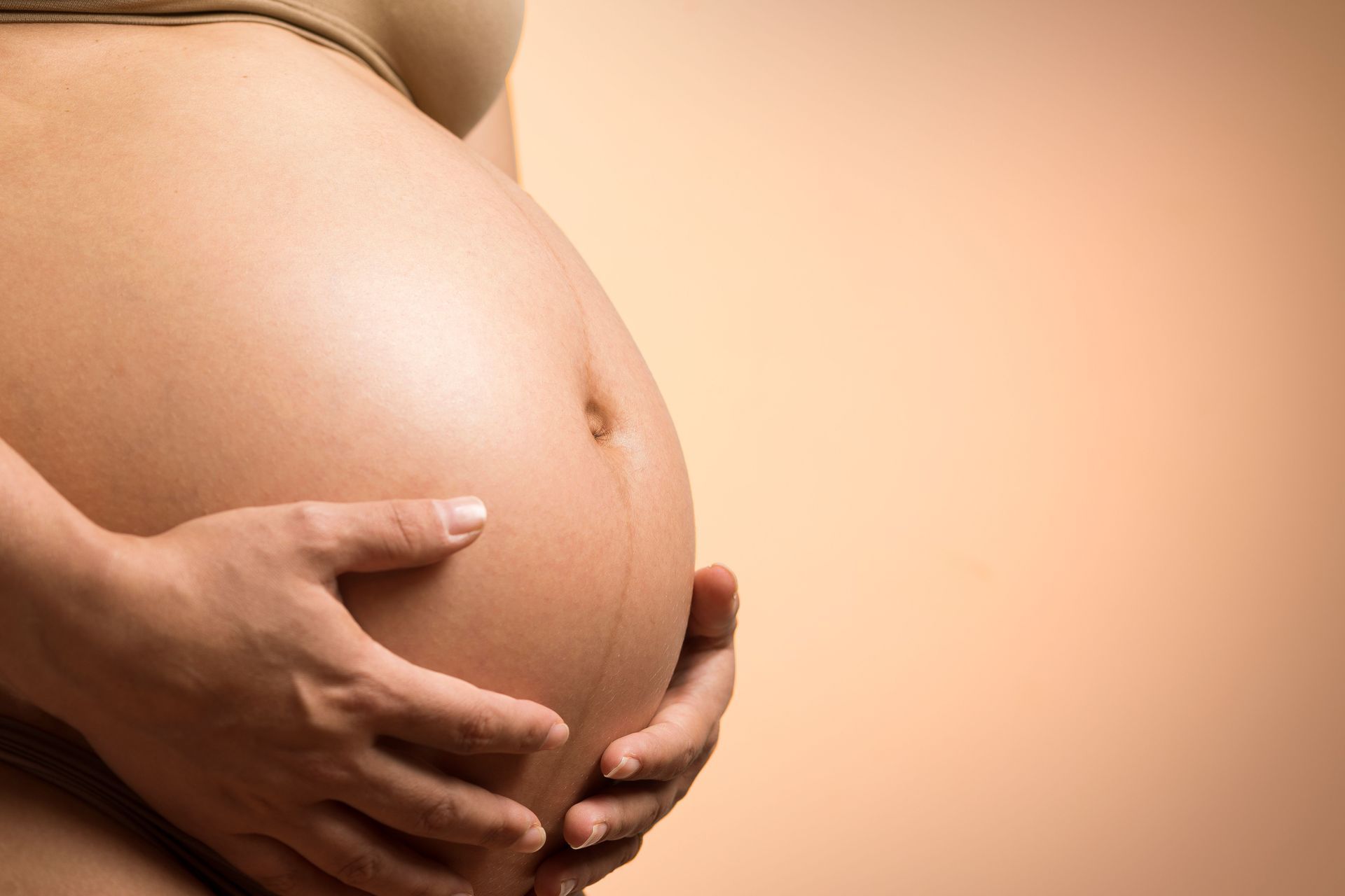 Pregnant belly with hands gently cradling
