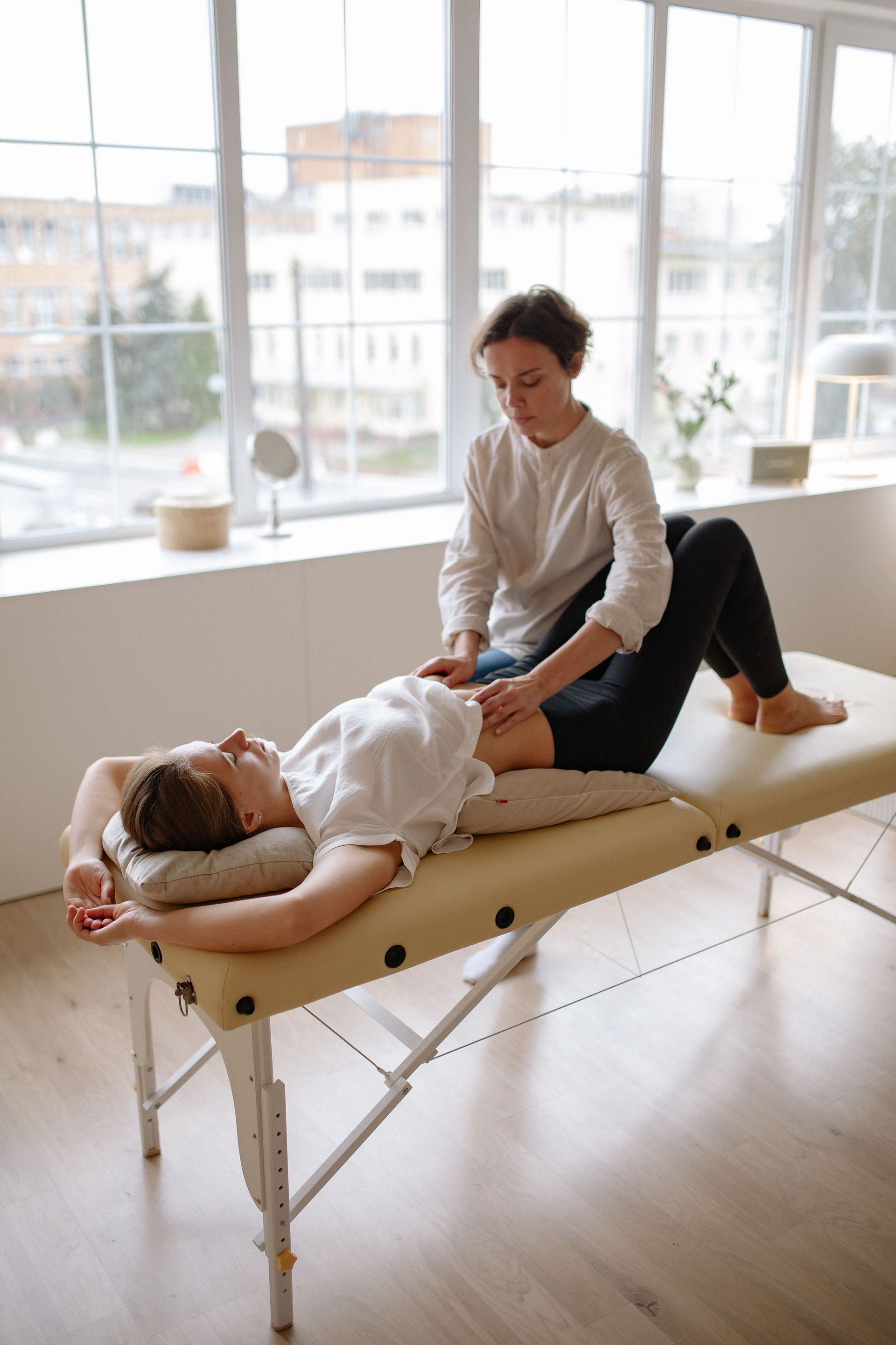 Massage therapist working on a client on a treatment table in a bright room