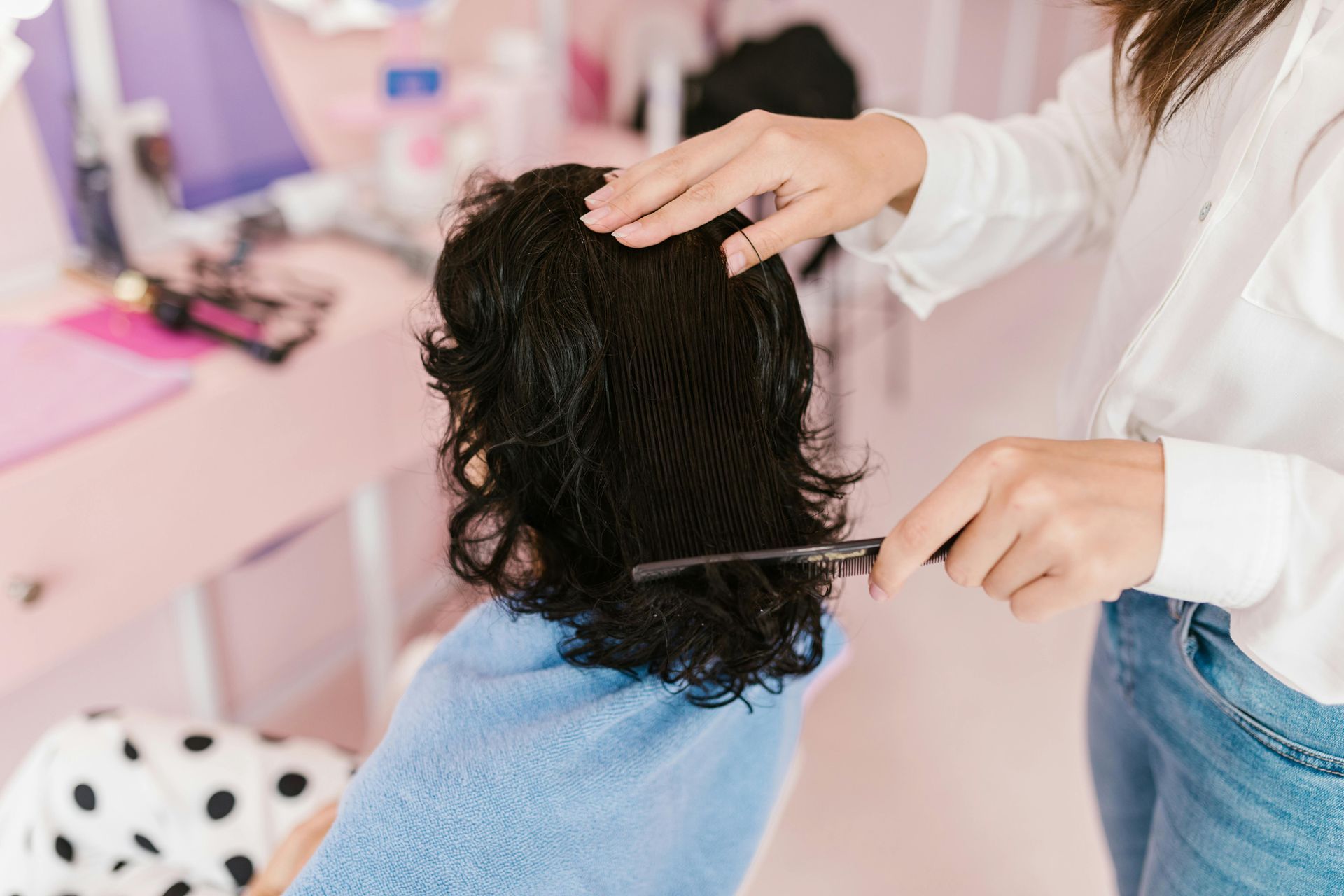 Person brushing curly hair topperin a pink salon chair