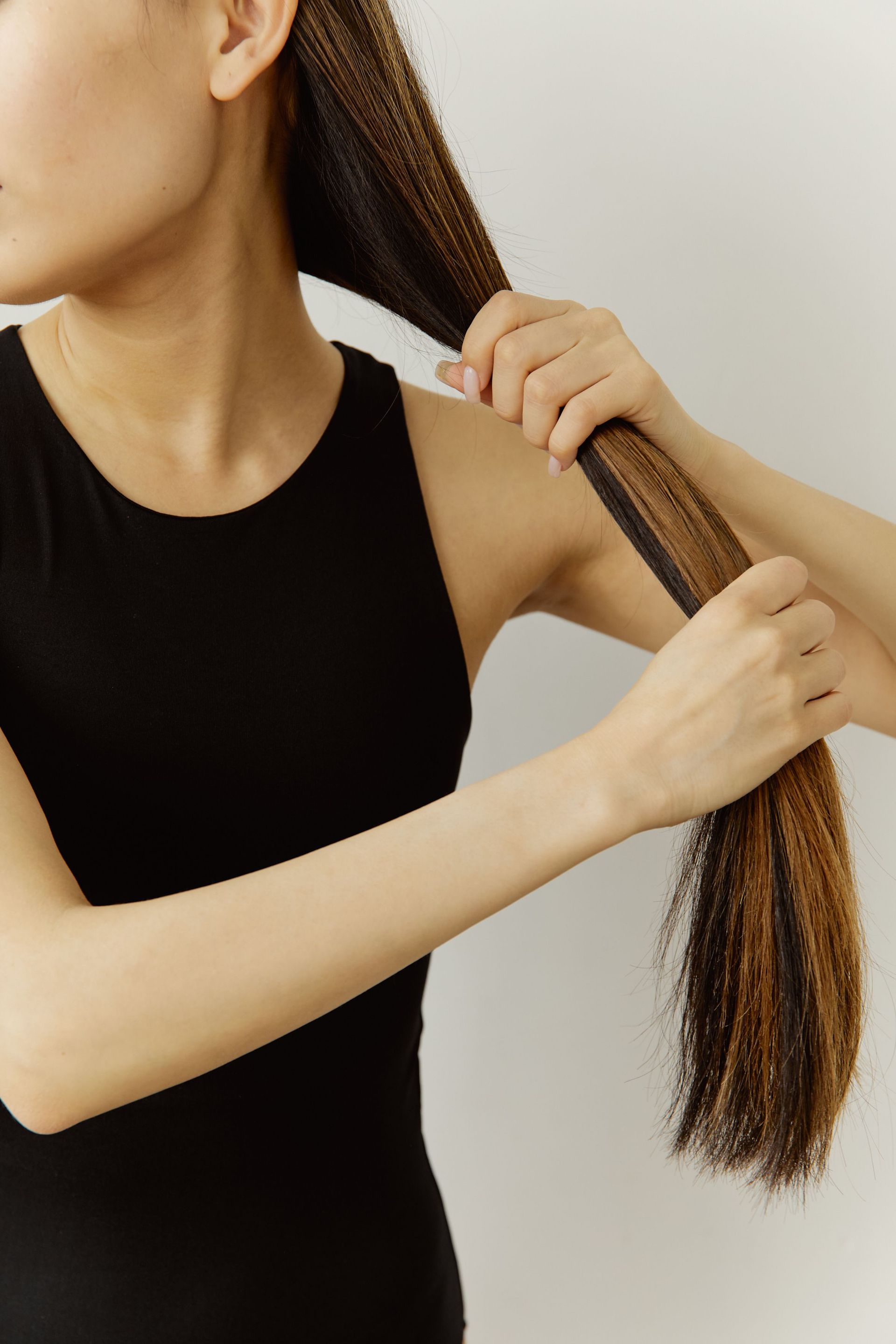 Person braiding long hair against a plain background