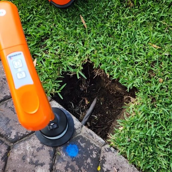An Orange Radar is Sitting on a Sidewalk Next to a Hole — Dowds Pipe and Cable Locating in Farmborough Heights, NSW