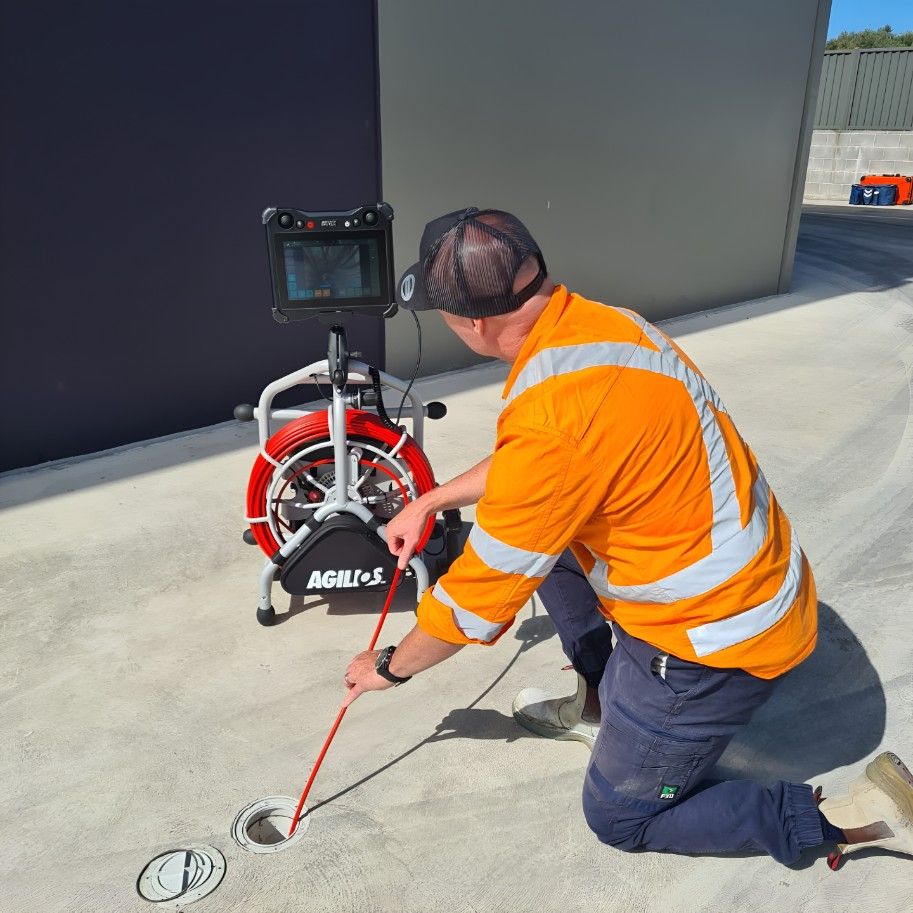 A Man is Kneeling Down in Front of a Radar Machine — Dowds Pipe and Cable Locating in Farmborough Heights, NSW