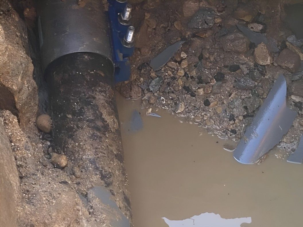 A Pipe is Sitting in the Dirt Next to a Puddle of Water — Dowds Pipe and Cable Locating in Batemans Bay, NSW