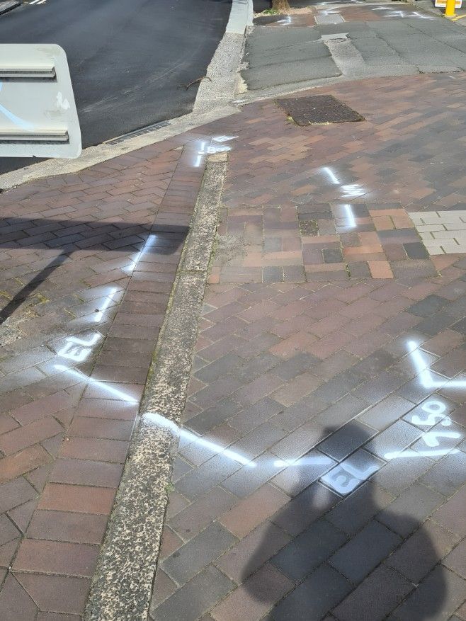 A Brick Sidewalk With White Lines Painted on It — Dowds Pipe and Cable Locating in Campbelltown, NSW
