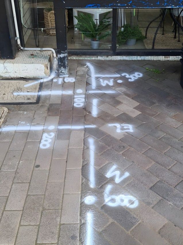 A Brick Sidewalk With White Spray Paint on It — Dowds Pipe and Cable Locating in Campbelltown, NSW