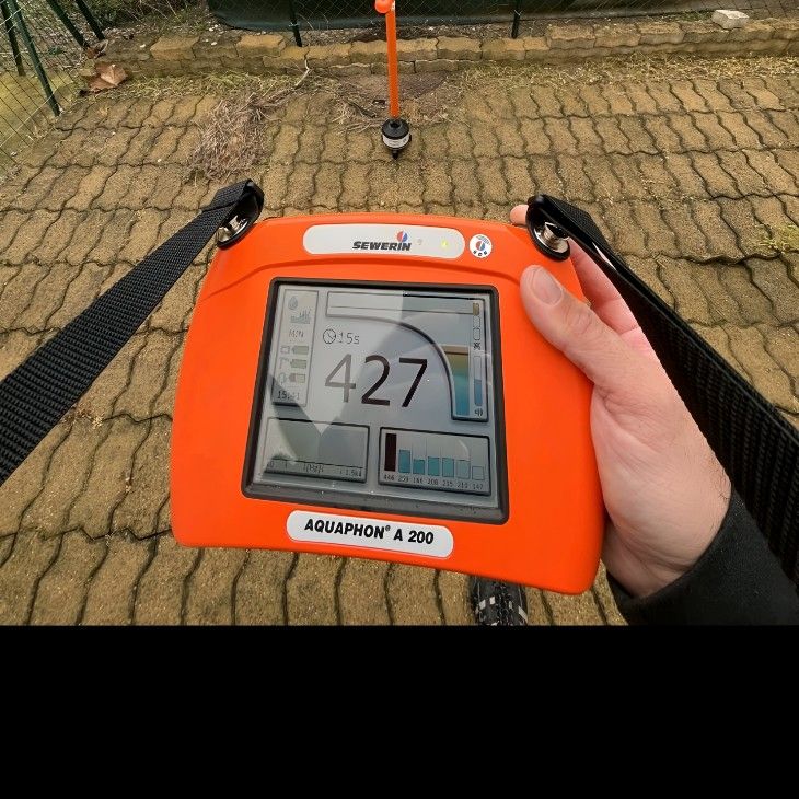 A Person is Holding an Orange Radar With the Number 427 on It — Dowds Pipe and Cable Locating in Goulburn, NSW