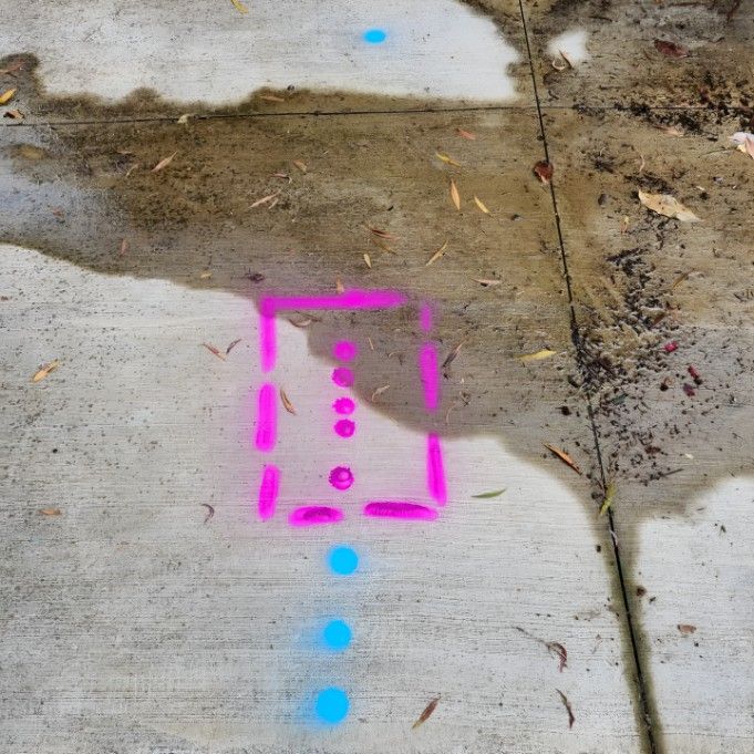 A Pink and Blue Square is Painted on the Sidewalk Next to a Puddle — Dowds Pipe and Cable Locating in Goulburn, NSW